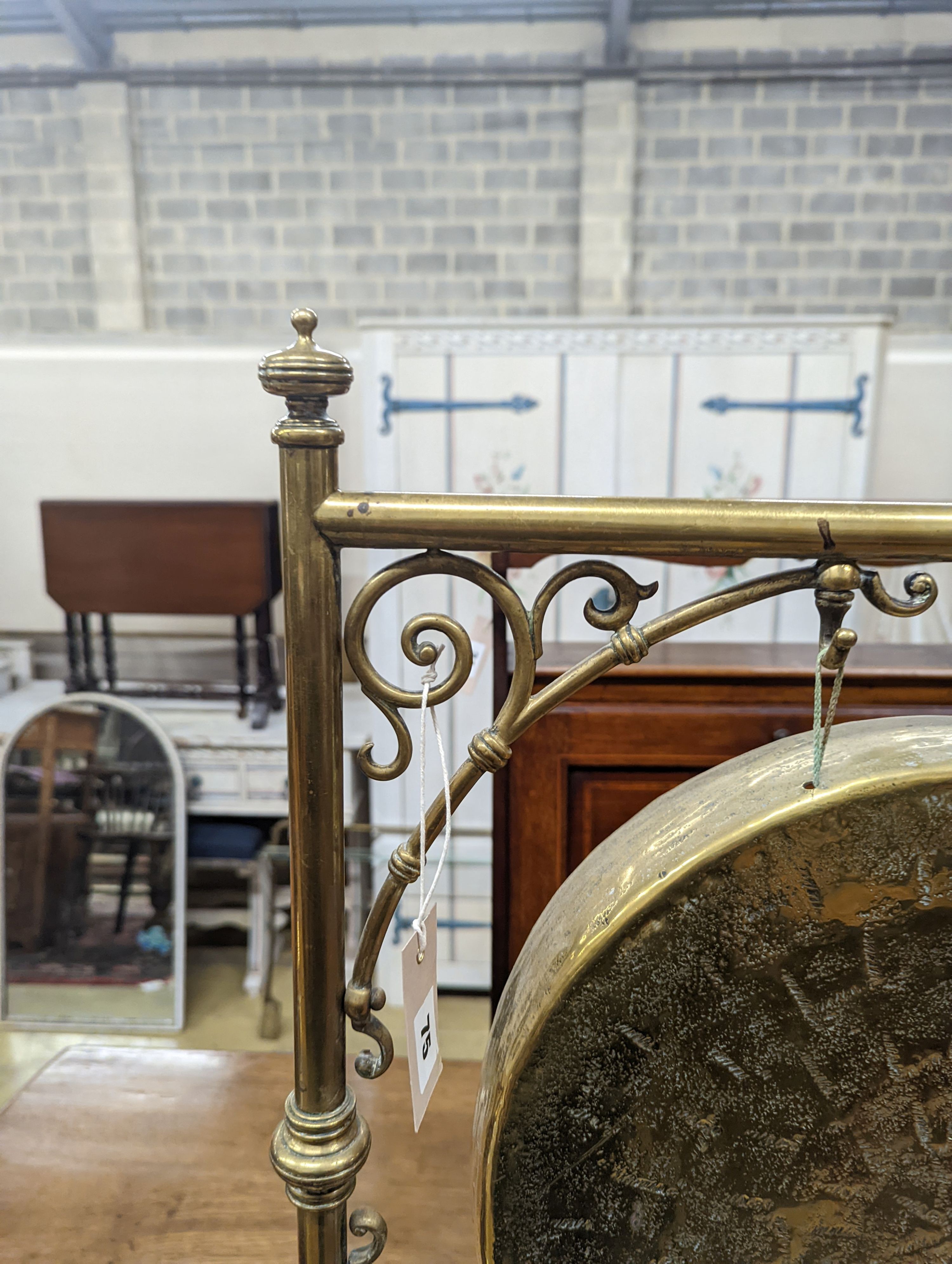 An Edwardian brass dinner gong with striker, width 50cm, height 84cm